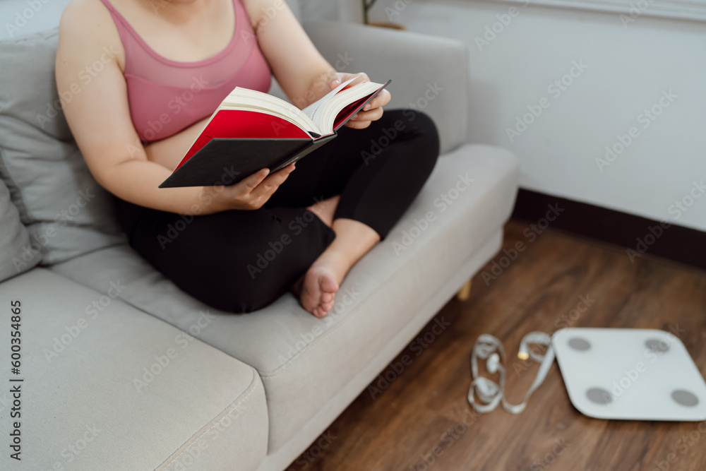 Obraz premium Overweight woman reading book for lose weight. Fat woman worried about weight diet Lose weight lifestyle