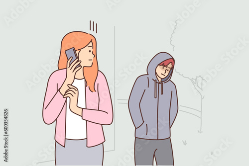Frightened woman with phone looks back at stalker and calls 911 to call police for help