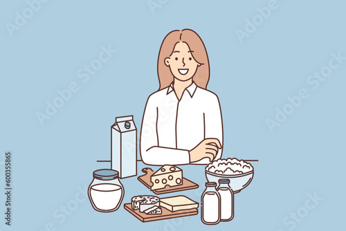 Woman is standing near table with dairy products and yogurt or cheese high in lactose and nutrients