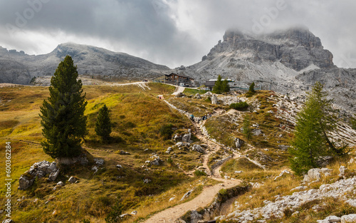 Rifugio Scoiattoli at Cinque Torri. Trail leading to the hut and 5 Torri top cable car station. Averau mountain in the clouds in the background. Nuvolao group near Cortina d'Ampezzo, Dolomites, Italy. photo