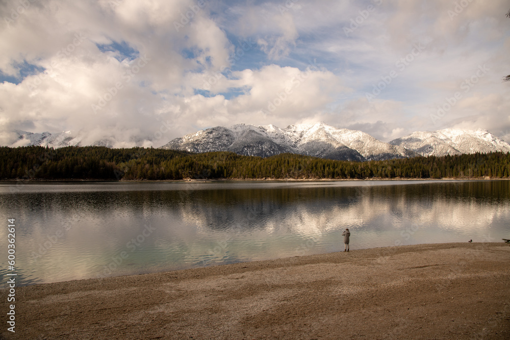 Landschaft in den Alpen mit Frau und See dem Eibsee, im Hintergrund schneebedeckte Berge Landschaft in den Alpen mit Frau und See dem Eibsee, im Hintergrund schneebedeckte Berge