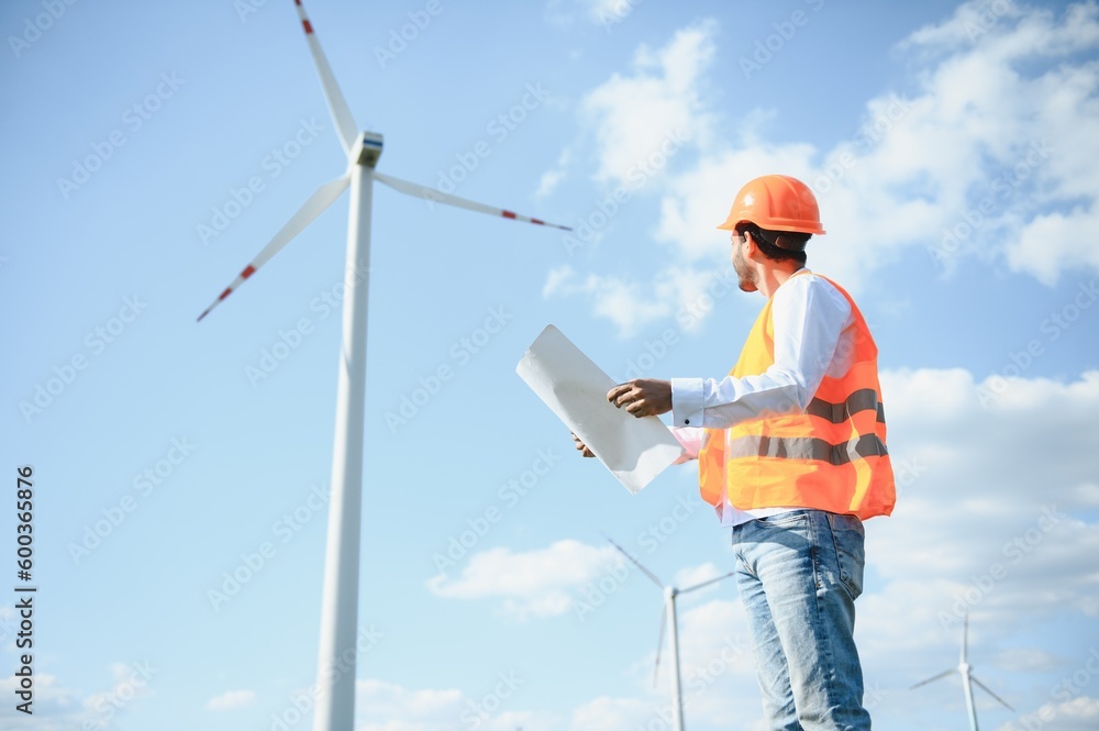 Portrait of focused indian man standing on field with wind turbines Portrait of focused indian man standing on field with wind turbines