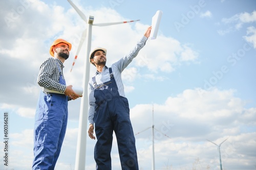 Two engineers discussing against turbines on wind turbine farm. photo