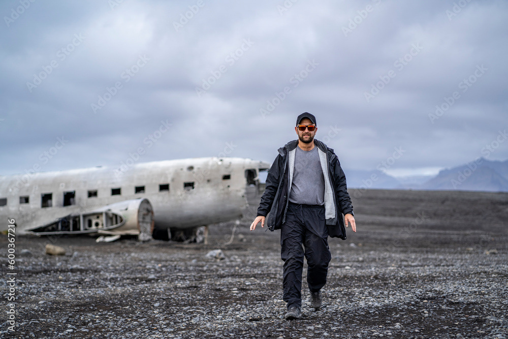 man walking away from United States Navy DC plane on the black beach at Sólheimasandur