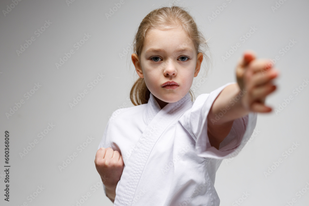 Portrait of a child girl on a gray background, karate training, punch. Portrait of a child girl on a gray background, karate training, punch.