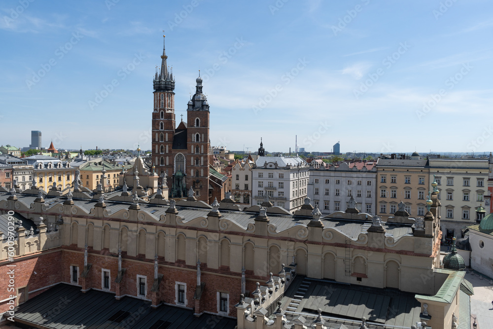 Fototapeta premium St. Mary's Basilica at the Main Market Square in the Old Town district of Krakow, Poland. Aerial view of Bazylika Mariacka or Kościół Mariacki Church Kraków, seen behind Cracow Cloth Hall Sukiennice.