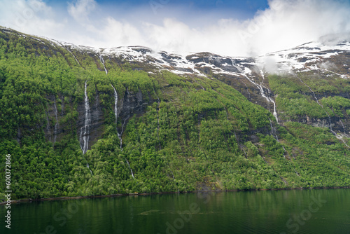 Beautiful landscape with snowy mountain peaks and waterfalls in Geiranger fjord, Norway