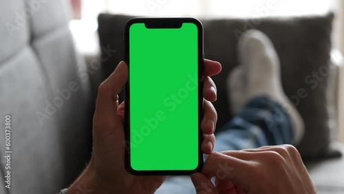 Single Tapping and Holding a Green Screen Smartphone on the Couch at Home