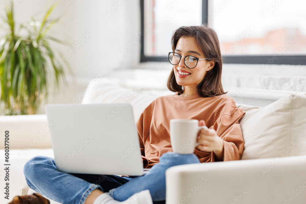 young beautiful woman drinking delicious hot coffee while surfing internet at laptop at home young beautiful woman drinking delicious hot coffee while surfing internet at laptop at home