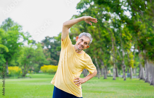 healthy senior man with grey hair fitness stretching before workout in the park, older adult warming up exercise among the nature, concept elderly people health care, wellness, wellbeing