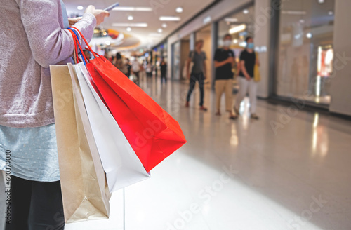 Woman holding many paper bags standing in spacious shopping mall. Shopping concept