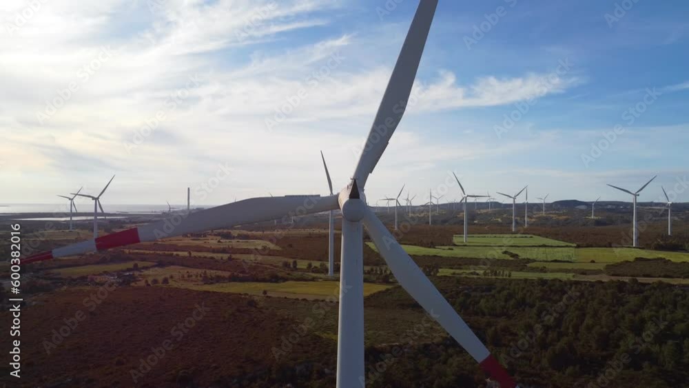 Aerial of wind turbine with blades rotating on a windy day, green landscape Aerial of wind turbine with blades rotating on a windy day, green landscape