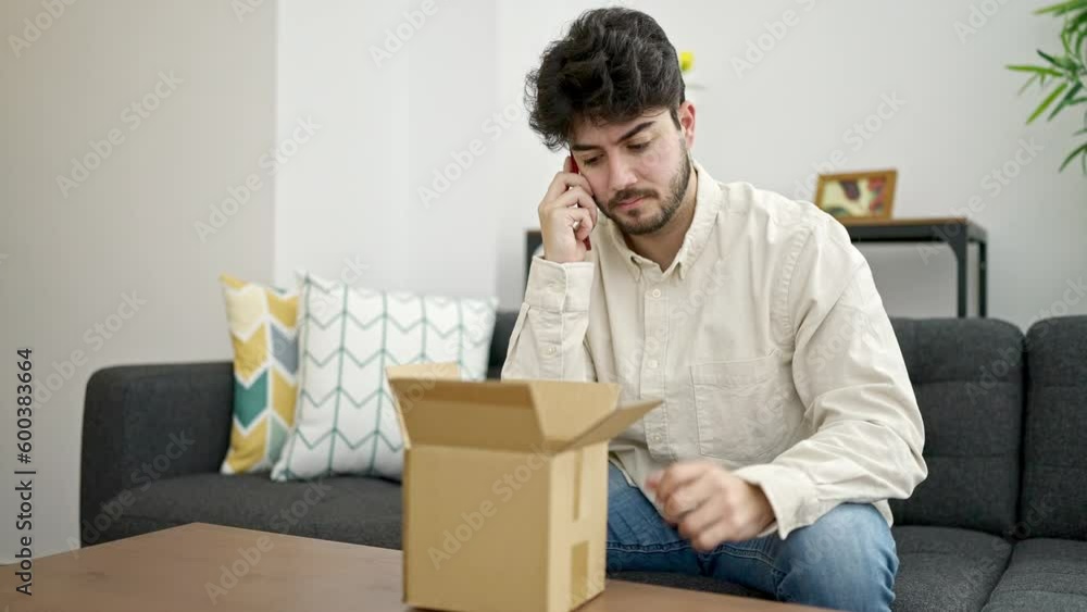 Young hispanic man speaking on the phone unpacking cardboard box at home Young hispanic man speaking on the phone unpacking cardboard box at home