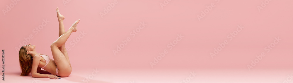 Portrait with smiling model, girl in underwear laying on floor with feet up over pink studio background. Banner with copy space for text, ad. Spa day Portrait with smiling model, girl in underwear laying on floor with feet up over pink studio background. Banner with copy space for text, ad. Spa day