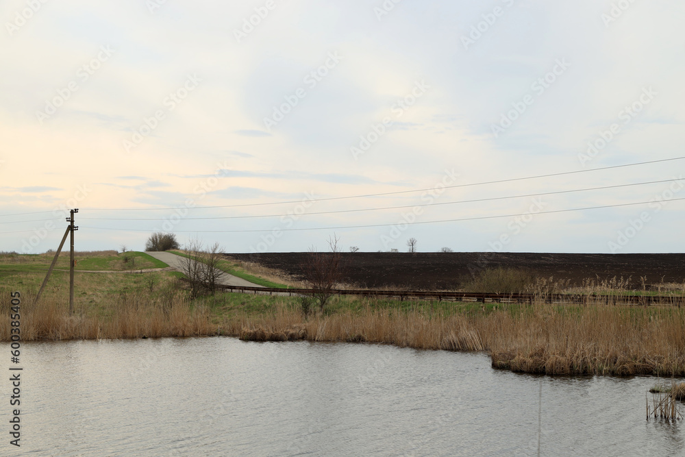 Lake, power lines, reeds and blue sky