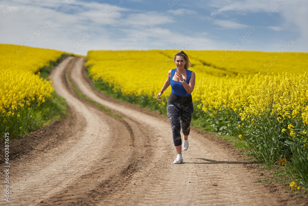 Plus size woman running on a countryside dirt road