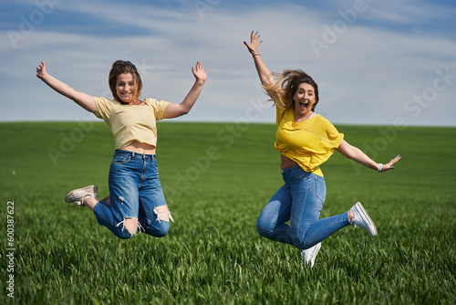 Plus size girls jumping for joy in a wheat field