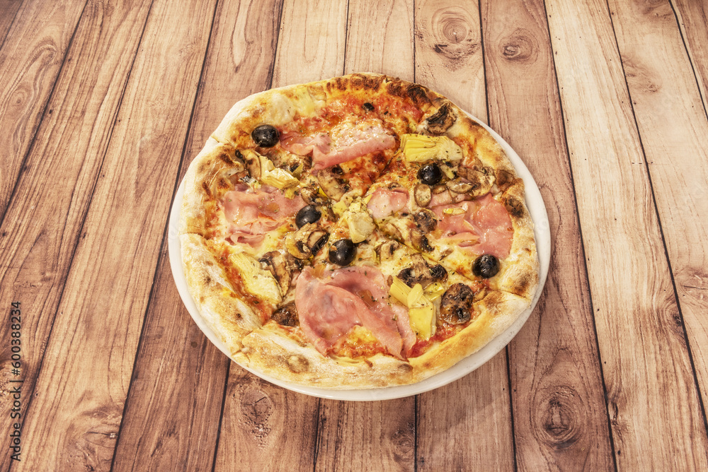 Whimsical Italian gastronomy pizza prepared with mozzarella cheese, oven-roasted Italian ham, artichokes,