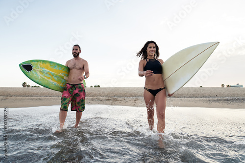 Friends with surfboards entering sea