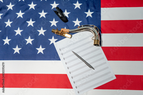 Close-up of female hands writing musical notes on a sheet of sheet music, against the background of the American flag photo