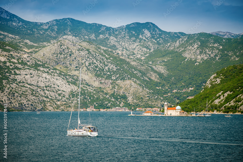 View of a floating white yacht near Our Lady of the Rocks in the Bay of Kotor View of a floating white yacht near Our Lady of the Rocks in the Bay of Kotor
