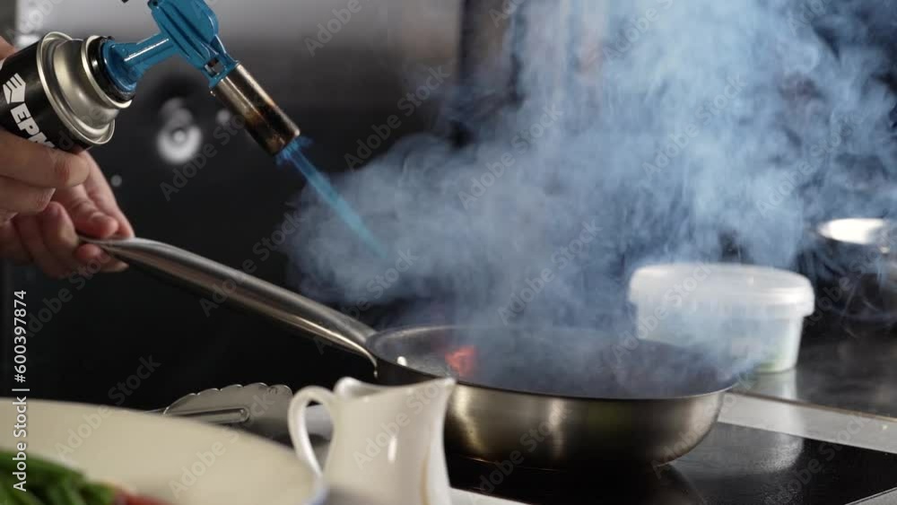 Chefs is cooking in a skillet with blazing fire. Chefs is cooking in a skillet with blazing fire.