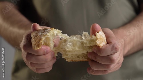 Man is tearing a piace of bread. close up on hands in slow motion photo
