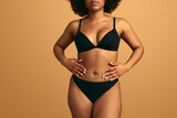Crop African American curvy lady touching belly in beige studio