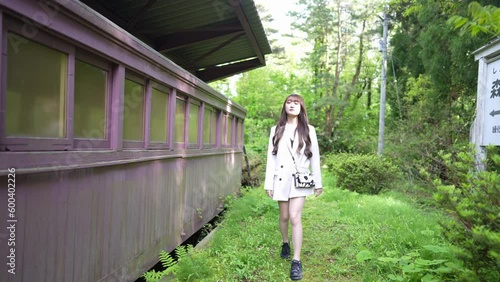 A young Japanese woman in her twenties, wearing a white jacket and shorts, walking through a forest in a large nature park in Tsubata Town, Kahoku District, Ishikawa Prefecture. photo