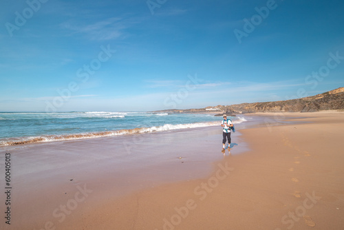 Fototapeta Naklejka Na Ścianę i Meble -  Backpacker walks along Praia do Almograve with a smile on his face. The joy of moving and discovering new places. Odemira region, western Portugal. Wandering along the Fisherman Trail, Rota Vicentina