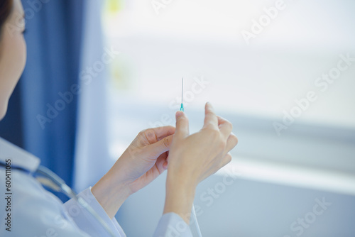 A doctor wearing a white coat is examining a syringe. to give injections to patients medical concept
