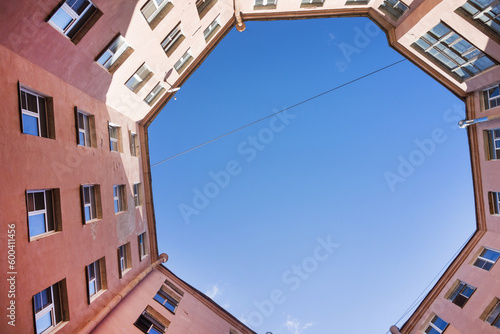 Saint Petersburg on sunny day. Well-houses typical of old city with narrow enclosed yards. View from below from courtyard-well of ring house to blue sky. Unusual urban landscape. Travel and city walks