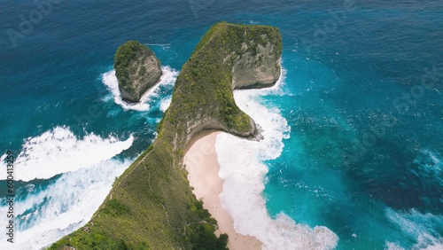 Kelingking sandy beach with tall overgrown rocky cliff and turquoise ocean Nusa Penida Island Bali. Aerial top down view of best tourist destination in Indonesia Asia.