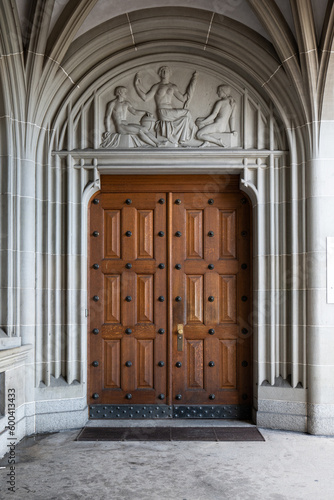 Old very large wooden entry brown door or gate. Decorated building arches, medieval european architecture, no people photo