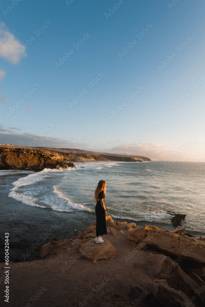 young woman enjoys the sunset on the coast of Fuerteventura while sightseeing in the Canary Islands
