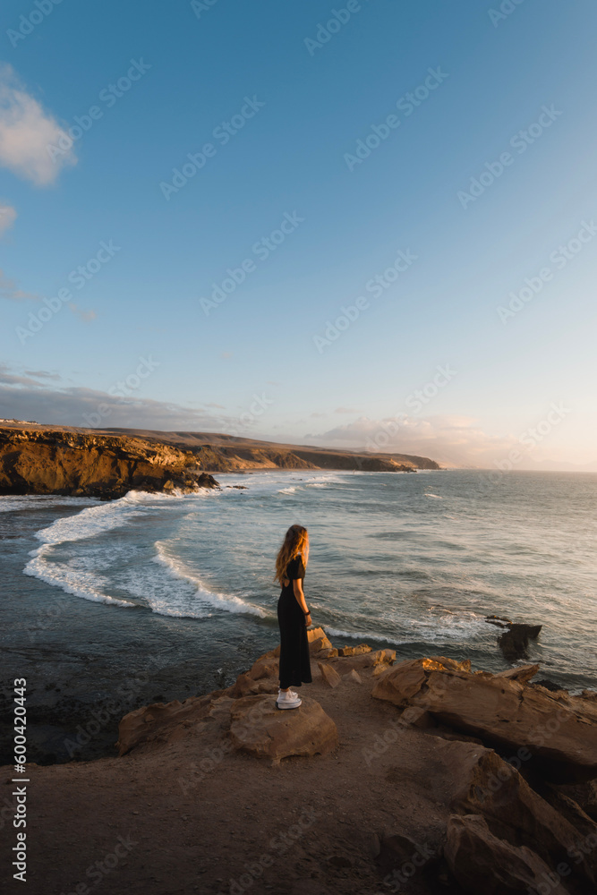 young woman enjoys the sunset on the coast of Fuerteventura while sightseeing in the Canary Islands young woman enjoys the sunset on the coast of Fuerteventura while sightseeing in the Canary Islands