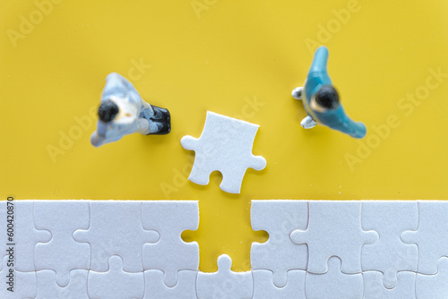 Top view photo of a business man lookg to White jigsaw or puzzle last piece to complete on yellow background with copyspace suitable for lat lay top view mock-up item,business concept. photo
