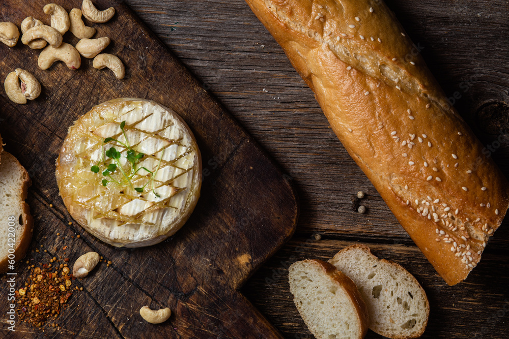 Baked Camembert cheese on a wooden board. Baguette Baked Camembert cheese on a wooden board. Baguette