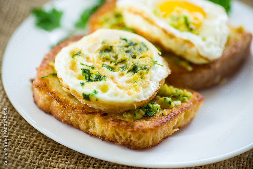 Fried croutons in batter with garlic and herbs and a fried egg in a plate. Fried croutons in batter with garlic and herbs and a fried egg in a plate.