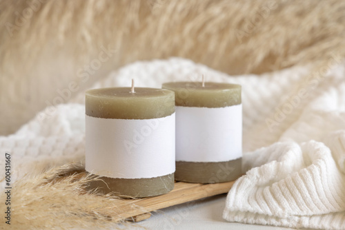 Candles with label on wooden tray near pampas grass and cosy sweater, Close up, mock up