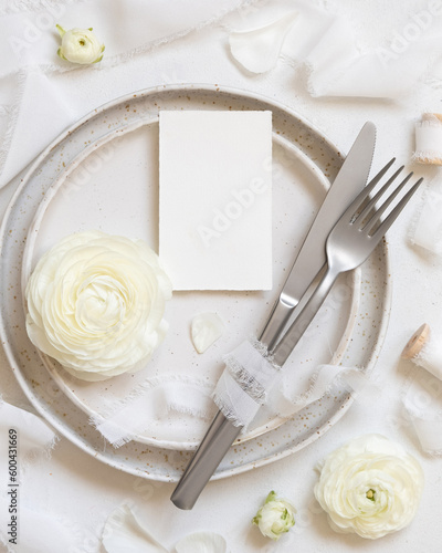Wedding table setting with small card near cream roses and white silk ribbons top view, mockup
