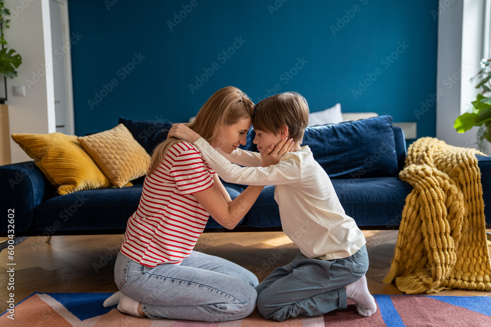 Affectionate empathic caring mom and teen son hug together sit on floor
