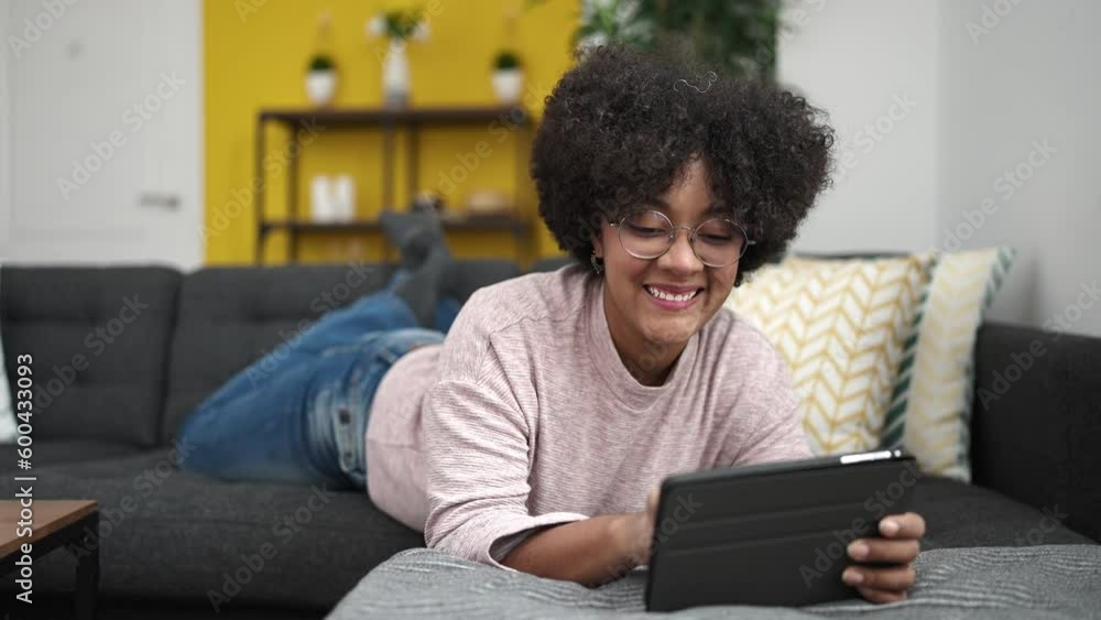 Young african american woman using touchpad lying on sofa at home Young african american woman using touchpad lying on sofa at home