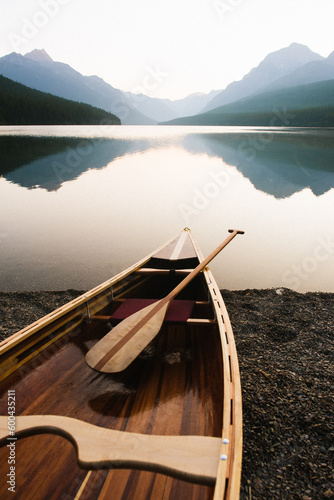 Canvas Print Wood canoe on the edge of Bowman Lake at sunrise in Glacier National Park, Monta