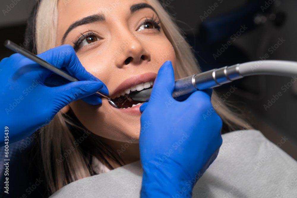 Dentist drills a tooth to a female patient in a dental chair. Closeup