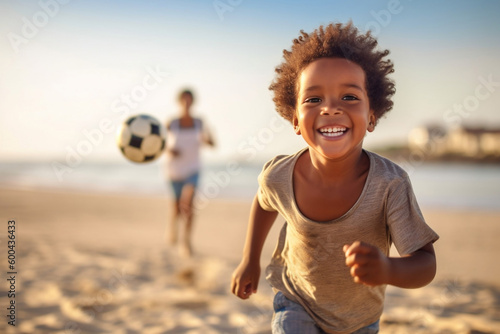 Mixed race black boy playing soccer on the beach summer time