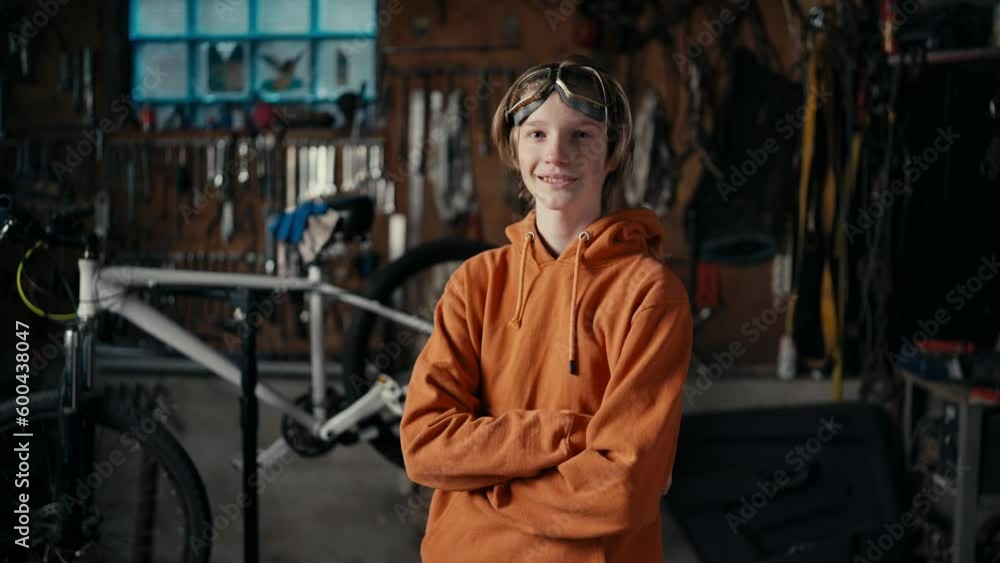 The Precision of Modern Manufacturing: A Teenager's Expertise. A teenager in goggles and an orange sweatshirt poses against the backdrop of a workshop The Precision of Modern Manufacturing: A Teenager's Expertise. A teenager in goggles and an orange sweatshirt poses against the backdrop of a workshop