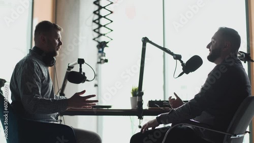 Two podcasters laughing and having fun in the studio. Two happy young people are doing a live audio broadcast together.