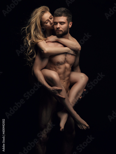 Two naked people on black background. Handsome couple in studio. Beautiful blond girl riding on fitness male model back.