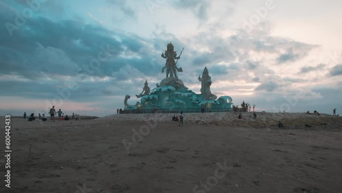 Pantai Jerman (German Beach) in Kuta, Bali Indonesia sunset shot showing statue of Varuna (The God of Sky, Water and Ocean) with people walking photo